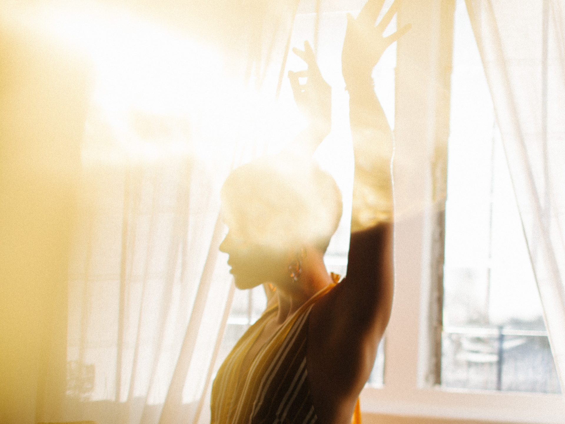 Une femme danse devant une fenêtre éclairée par le soleil.