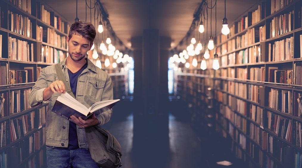 Un étudiant lit un livre dans une bibliothèque