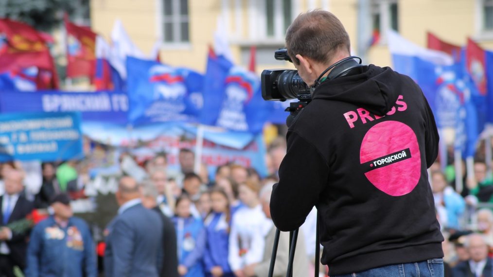 Un journaliste filme une manifestation avec sa caméra.