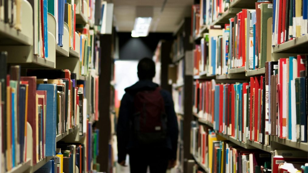 jeune homme de dos dans une bibliothèque