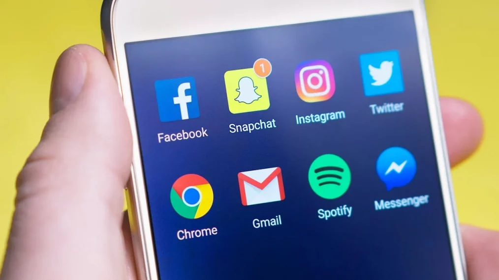 Un ado tient un téléphone portable avec des applications.