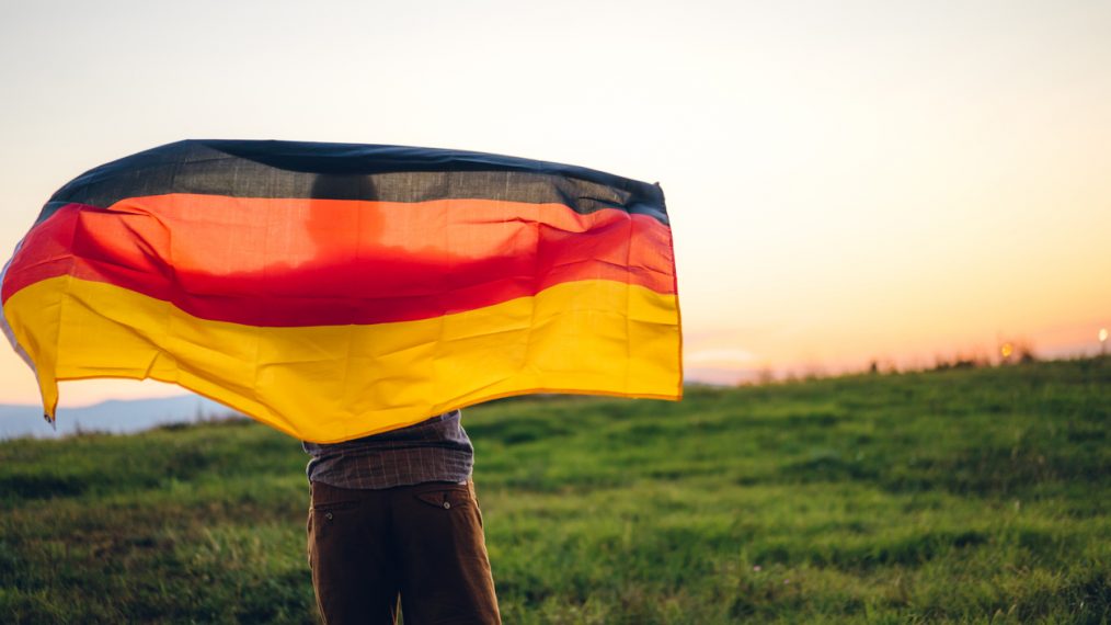 Une personne porte un drapeau allemand.